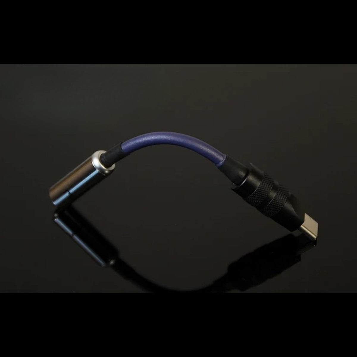 USB-C headphone DAC dongle arched on reflective black surface