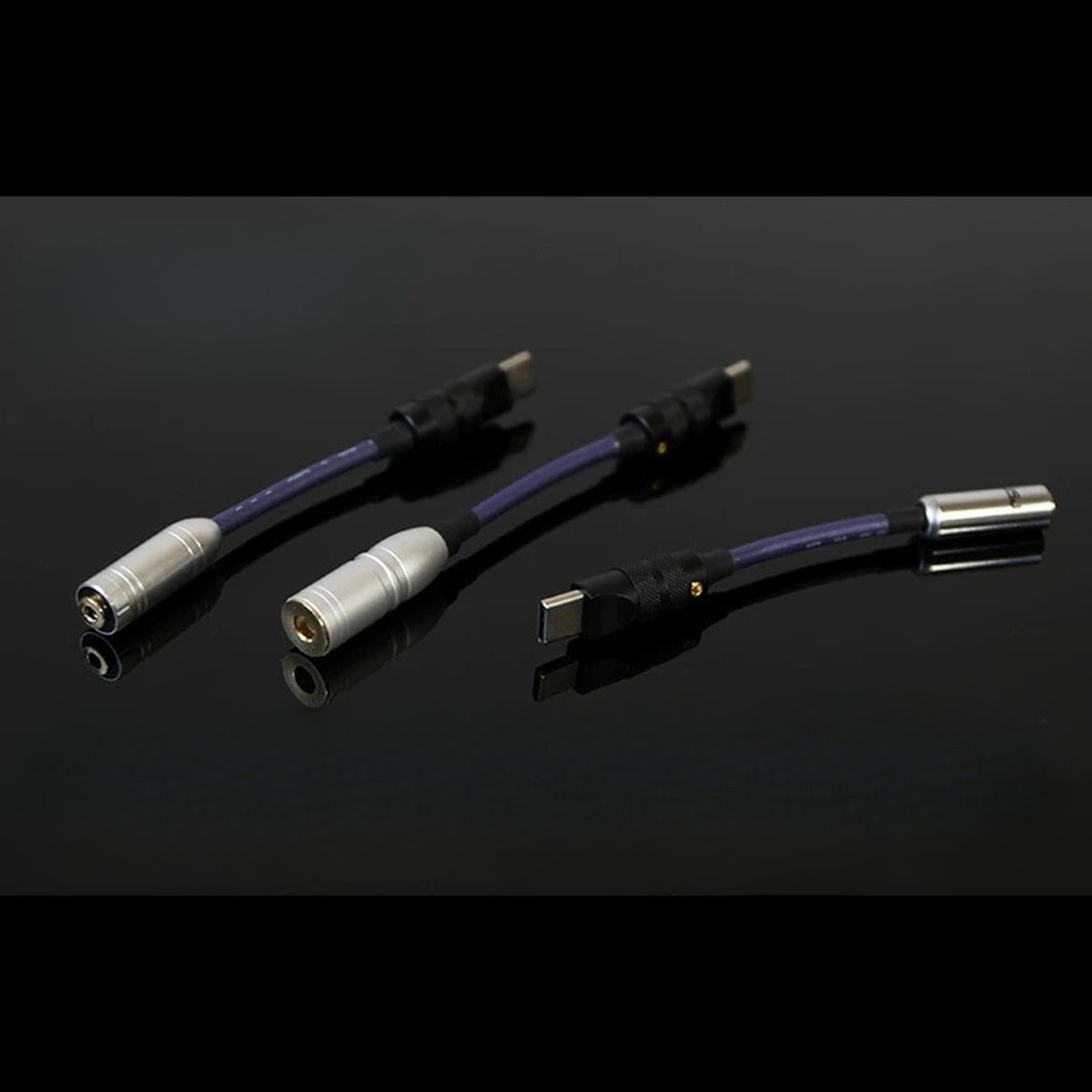 USB-C headphone DAC dongles on reflective black surface